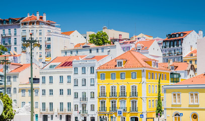 Fototapeta na wymiar Portugal, Lisbon in summer, street of Lisbon, beautiful yellow house among white houses in Lisbon, forged balconies on the yellow wall, Lion statue in Lisbon