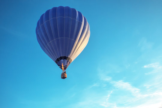 Big blue hot air balloon flying in light blue sky with copy space