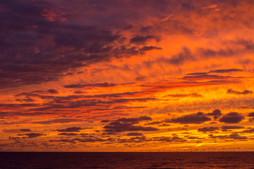 Fototapeta na wymiar Beautiful orange and yellow evening sky with many clouds over the sea. Dramatic sky.