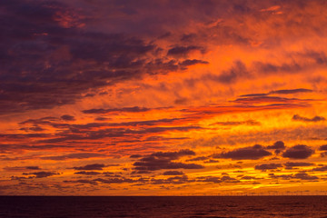 Obraz premium Beautiful orange and yellow evening sky with many clouds over the sea. Dramatic sky.