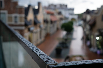 Obraz premium Rain drops on dark railing in autumn city in cloudy weather. on the blurry backdrop of the city streets.