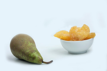 a bowl of dried pears and a green pear isolated on white background. Horizontal image