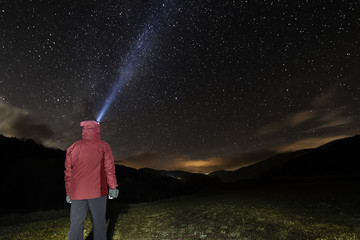 man with headlamp looking at the starry night sky