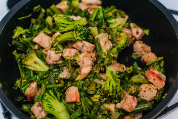 Stewed vegetables in a pan with fried chicken. Stir with a wooden spatula while cooking