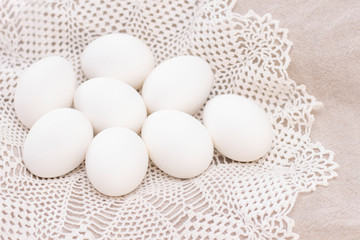 pile of organic white eggs of chicken healthy eating freshness on a brown bag and a white beautiful knitted napkin. for background texture soft focus close-up