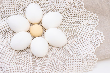 organic white eggs of chicken freshness healthy nutrition on a brown bag and a white beautiful knitted napkin in the shape of a flower. In the middle is a boiled yolk. for background texture