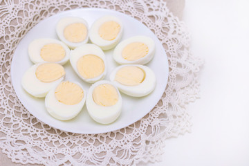 organic white eggs of boiled healthy food chicken on a white plate and a white beautiful knitted napkin. for background texture soft focus close-up