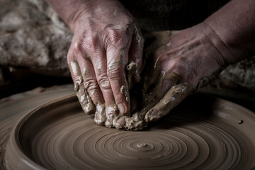Hand craft making pottery on wheel. Female hands mold ceramic plate from clay