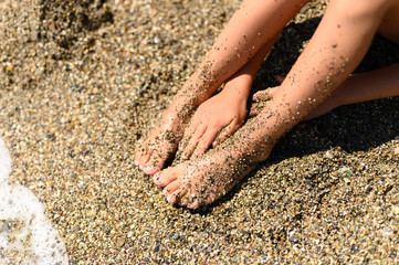 children's feet in the sea sand and water