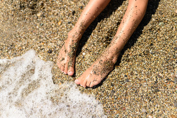 children's feet in the sea sand and water