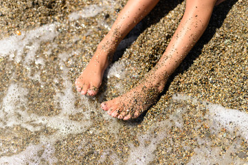 children's feet in the sea sand and water