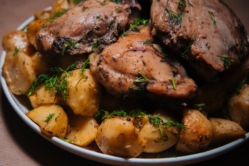 Fried chicken legs with chips sprinkled with dill and greens on a large plate. Baked dish. Golden Potatoes