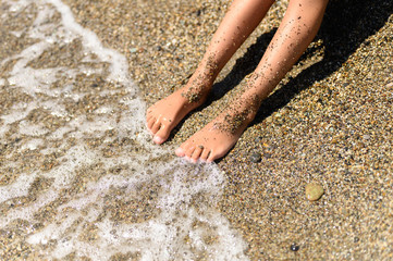 children's feet in the sea sand and water