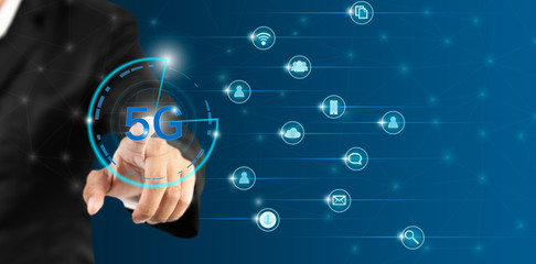 Business man puching on 5G icon on blue background. Background of the 5g Systemless Communication Network. © amornchaijj