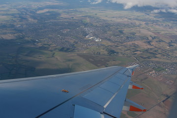 Fototapeta na wymiar wing of airplane flying above countryside