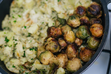 Potatoes with greens in a pan and fried Brussels sprouts. Stewed potatoes with dill.