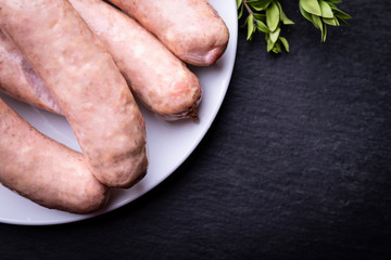 White, boiled sausage on a plate on a dark background.