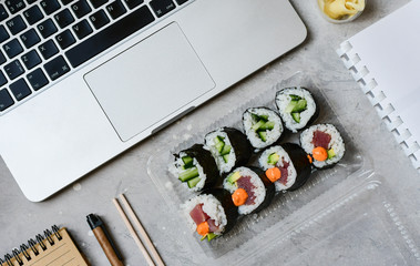 Food delivery. lunch box with sushi roll with tuna, avocado, cucumber and soy sauce on a gray office desk. takeaway lunch at the office. sushi menu delivery. Selective focus