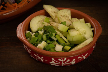 Sliced cucumber and green onion in clay dish