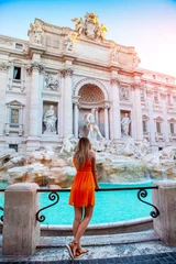 Foto auf Acrylglas Mädchen in orangefarbenem Kleid vor dem Trevi-Brunnen, junges hübsches Mädchen mit blonden Haaren in einem orangefarbenen/gelben Kleid. Schöne Frau in der Nähe von Trevi-Brunnen, Rom, Italien. Glückliches Mädchen genießt den Urlaub. © Epic Vision