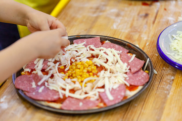 Children cooking pizza. Photo of children hands cooking Italian food. Process of cooking pizza by children in the master class. 
