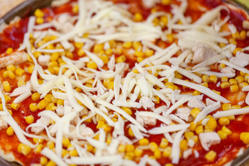 Uncooked salami pizza . Fresh homemade traditional unbaked italian pizza with tomatoes,  corn, cheese and salami on wooden cooking table with ingredients.