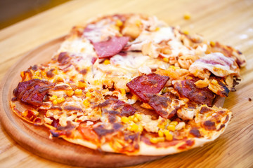 Pizza on wooden platter. Burnt pizza. Junk food, fat, unhealthy eating, bad habits. Fresh italian pizza with salami, tomato and cheese served on. Italian traditional meal