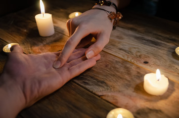 woman fortune-teller reads the lines of a man's hand and predicts his future, hands on a wooden...