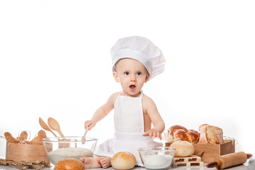 child with bread on bakery-like background wearing cook-hat. Little baker