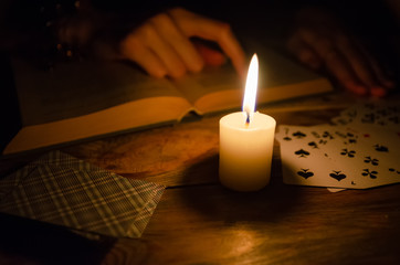 Cards, a book, a candle, a hand on a wooden table. study of magic. concept of divination, magic.