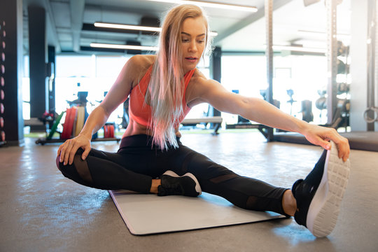 young pretty woman is stretching in the gym before exercise