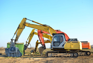 Group tracked excavators at a construction site. Special heavy construction equipment for road construction, road repair, laying of underground sewer pipes. Crushing bucket for crushing concrete.