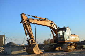 Excavator digs the ground for the foundation and construction of a new building. Road repair, asphalt replacement, renovating a section of a highway, laying or replacement of underground sewer pipes