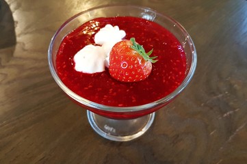 Glass bowl with strawberry jam and strawberries on the table