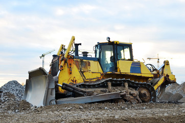 Bulldozer during of large construction jobs at building site. Land clearing, grading, pool excavation, utility trenching and foundation digging. Crawler tractor,  dozer, earth-moving equipment.