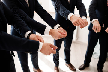 groom and his groomsman friends in stylish suits preparation before the wedding in the morning , emotional group of friend. cropped photo