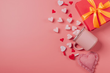 pink mug on a pink background filled with marshmallows in the form of hearts. next to it is a box with a gift for Valentine's Day. valentine's day holiday concept
