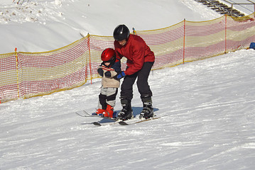 grandfather teaches grandson skiing