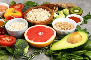 Healthy food clean eating selection: fruit, vegetable, seeds, superfood, cereals, leaf vegetable on rustic background