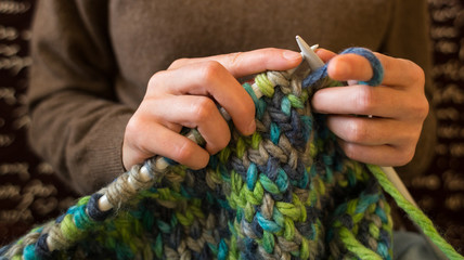 A woman knits from thick yarn.