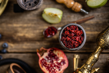 Hookah components on a rustik old wood table with fruits, tobacco and cocoa coal for shisha