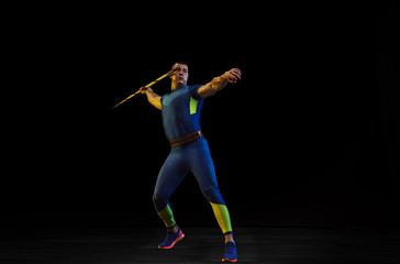 Fototapeta na wymiar Male athlete practices in throwing javelin on black background in neon light. Professional sportsman training in action, motion. Concept of healthy lifestyle, movement, activity, competition
