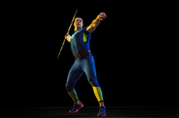 Male athlete practices in throwing javelin on black background in neon light. Professional sportsman training in action, motion. Concept of healthy lifestyle, movement, activity, competition