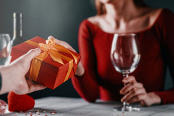 Congratulation concept for valentines day. couple at the table in a restaurant. dim lights, lovers give each other gifts.