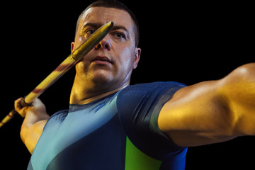 Male athlete practices in throwing javelin on black background in neon light. Professional...