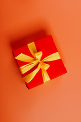 red box tied with a gold ribbon. the ribbon is tied on a box in the form of a beautiful bow. holiday gift concept