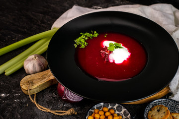 beetroot soup with the addition of cream and fresh parsley in a black plate