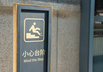 Warning sign of slippery floor with the word mind your step in English and Chinese Word. Caution warning on step symbol.