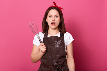 Image of astonished good looking female standing isolated over pink background in studio, opening...