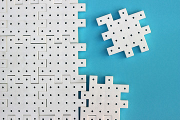 White puzzle pieces on the  turquoise background show cohesion, teamwork and agreement.
